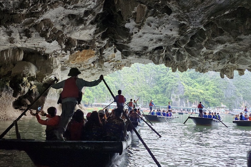 Kayak passing under the low arch of Luon Cave Halong Bay