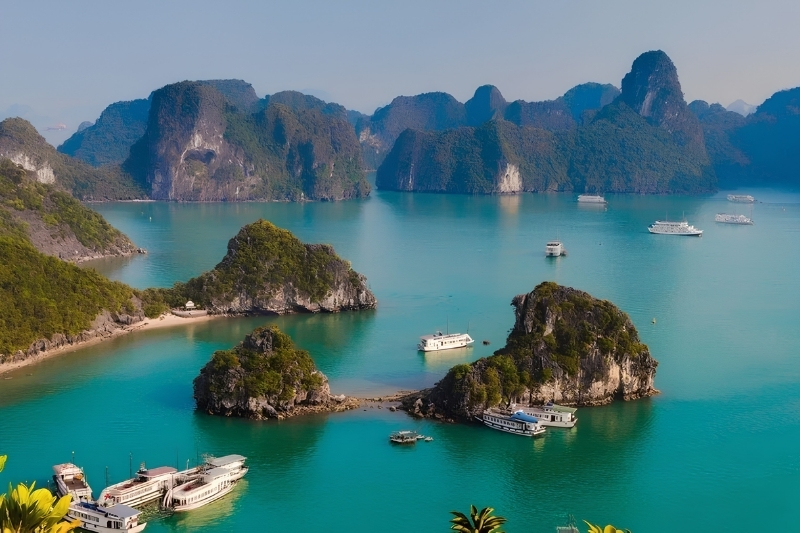 A luxury white cruise ship sailing through the tranquil, emerald waters of Ha Long Bay surrounded by thousands of towering limestone islets.