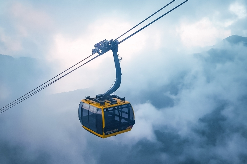 A modern three-cable car cabin gliding smoothly over the deep green Muong Hoa Valley, carrying visitors toward Ga Fansipan.