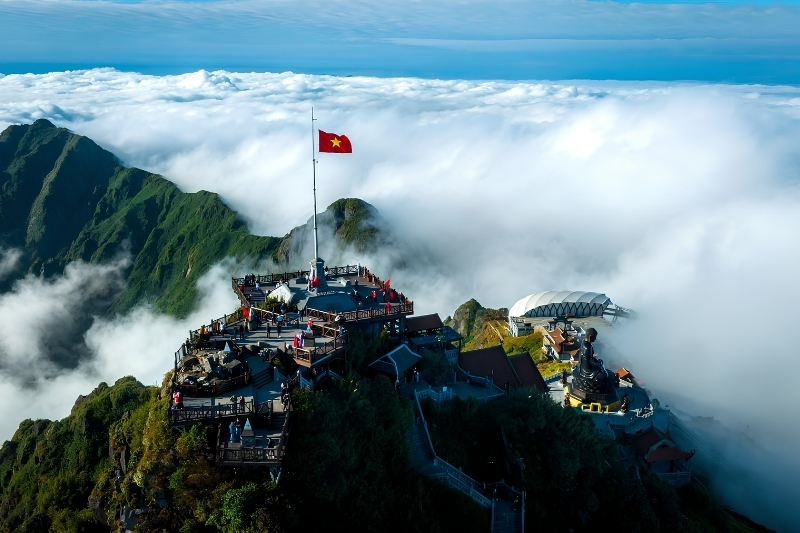 The majestic, jagged peaks of the Hoang Lien Son mountain range surrounding the prominent summit of Fansipan under drifting mountain mist.