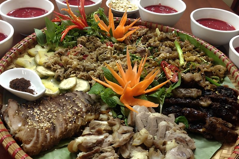 What is "Armpit" Pork (Thit Lon Ban) in Sapa? A platter of golden-brown, crispy roasted armpit pork slices served with wild mountain herbs and dipping sauces.