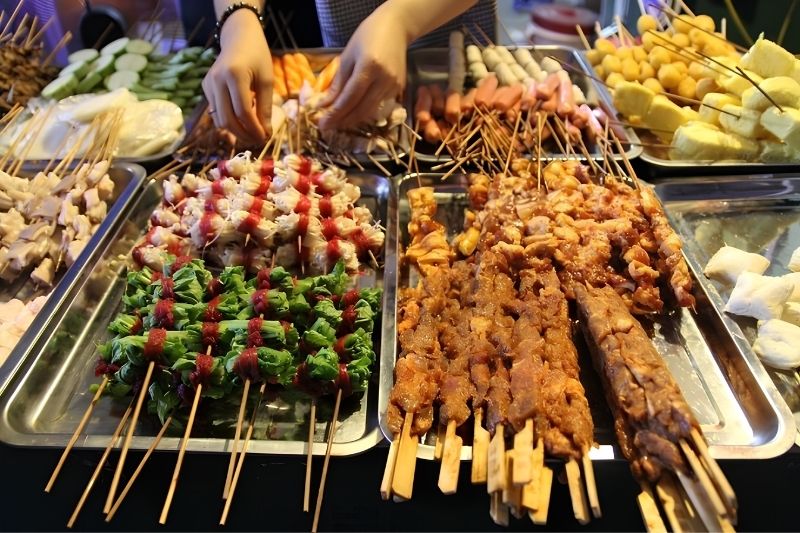 Sapa Street-Side Grills: Ultimate Sapa Night Market Food Various colorful skewers of mushrooms wrapped in beef, local vegetables, and seafood grilling over hot charcoals at a Sapa street stall.