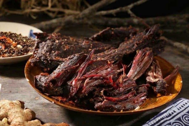 Smoked Buffalo Meat: Sapa's Signature Highland Flavor Dark-colored, dry strips of authentic smoked buffalo meat being shredded and served with local Cham Cheo dipping sauce.