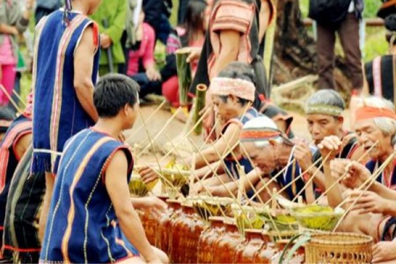 Clear Ban Pho corn wine being poured into a small rustic ceramic cup next to traditional wooden distilling barrels in a Hmong stilt house.
