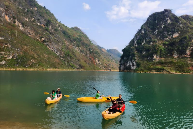 Kayaks on the green water of the Nho Que River